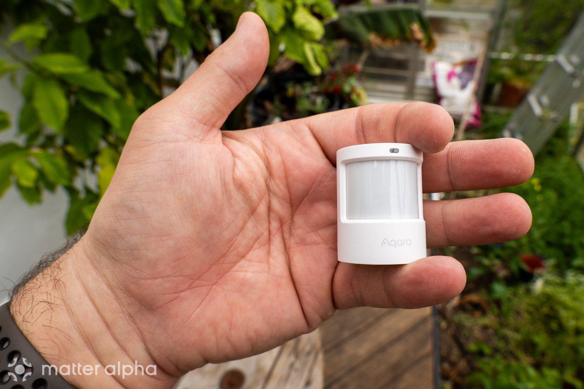 Aqara p2 motion sensor being held in hand to show minuscule size